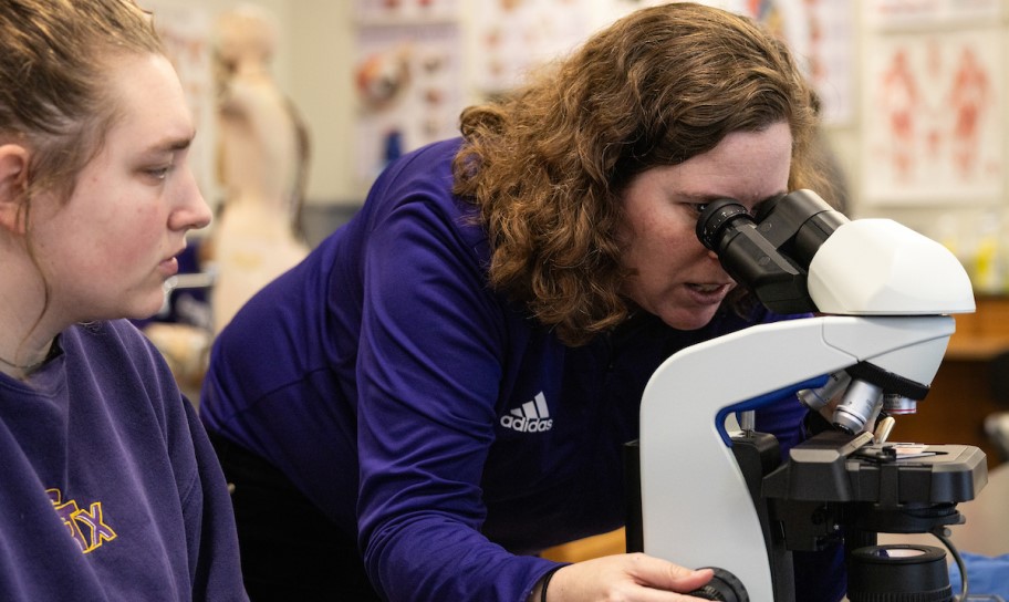 Concordia Texas professor assiting a student in lab with a microscope