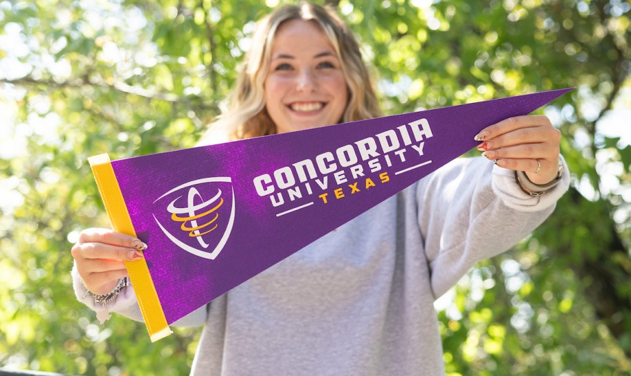 Concordia Texas student holding up the university pennot.