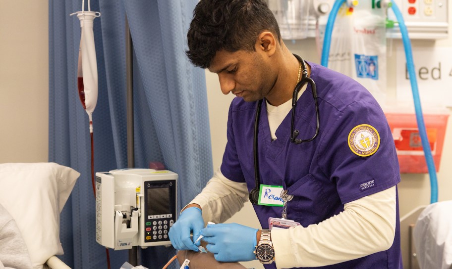 A nursing student working in a sim lab on campus